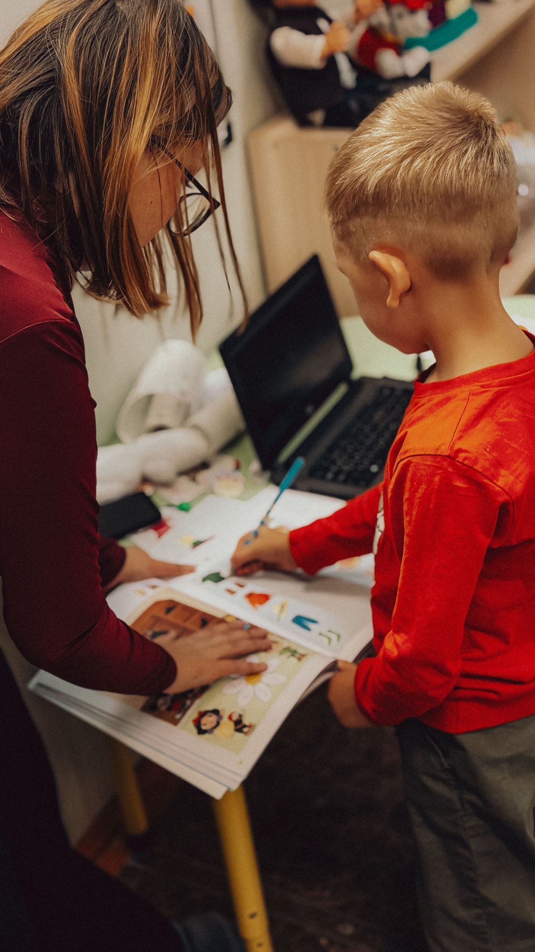 Occupational therapist supporting a young boy with a table-top learning activity