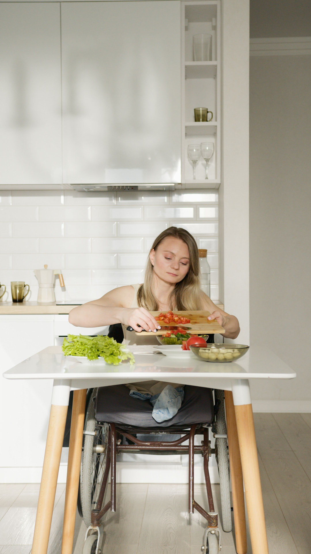 Woman using a wheelchair preparing a meal independently in her kitchen