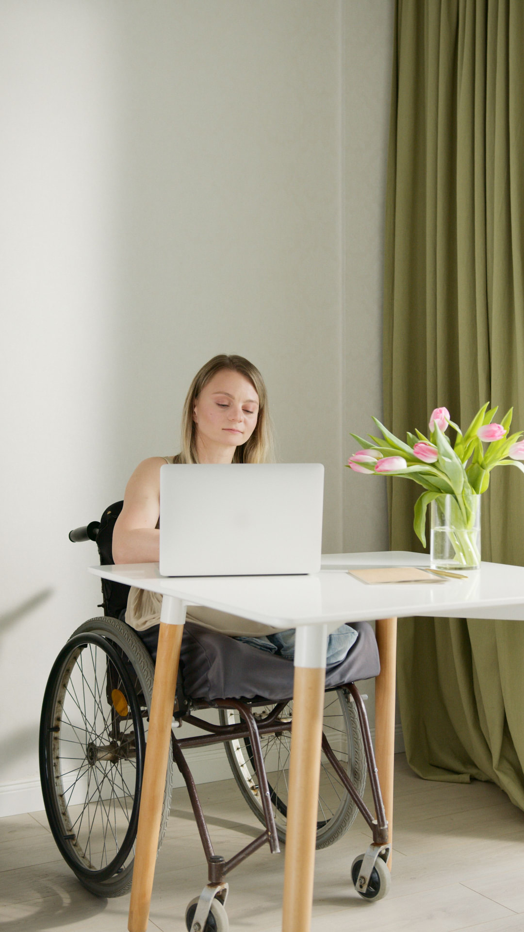 Adult wheelchair user working at a desk at home