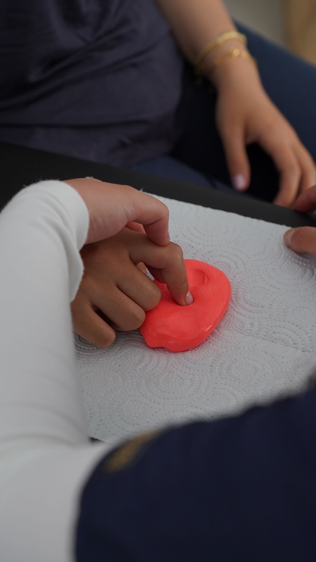 Child shaping modelling clay during a fine motor therapy task